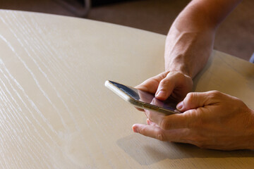 Closeup on hands of man using cellphone on table. Business, copy space concepts