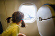 © Cavan Images - Little girl with pigtails sits on plane staring out window on tarmac