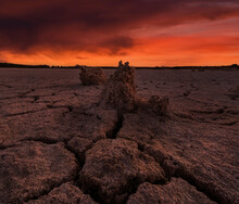 Drought Landscape With Cracks In Ground Without Water With Red Sky