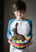 Young happy boy holding Easter basket full of eggs and chocolate bunny
