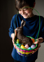 Young Happy Boy Holding Easter Basket Full Of Eggs And Chocolate Bunny