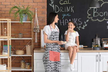 Young mother and daughter with tasty muffins in kitchen at home