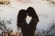 © Cavan Images - romantic pastel coloured silhouette of lesbian queer couple by lake