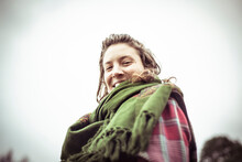 Happy Natural Woman In Green Scarf And Flannel Shirt Looks Down Smiles