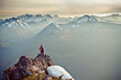 © Cavan Images - Hiker standing on the edge of a cliff looking out at scenic mountians