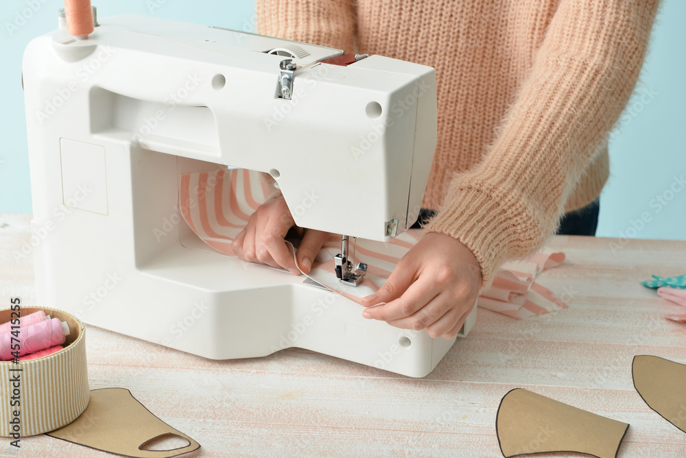 Young woman sewing clothes at table