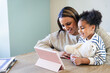 © Cavan Images - Smiling daughter and mother using digital tablet at home