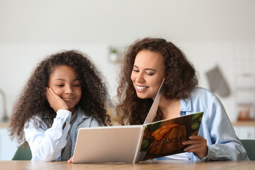 Canvas Print - African-American little girl with her mother reading book at home