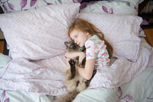 Sick Little Girl Cuddling Cat In Bed