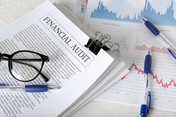 Financial audit documents, glasses and pen on table