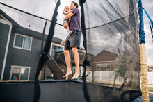 Dad Bouncing On The Trampoline With Toddler Son