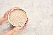 © Cavan Images - Top view of hands holding a bowl of raw white rice with copy space