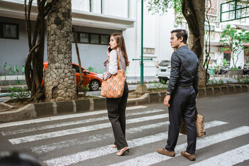 man and woman are walking crossing the road