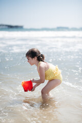 Wall Mural - child playing on the beach with bucket in ocean