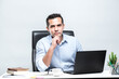 © maya1313 - Asian male office worker sitting in front of a laptop computer at a desk and smiling at the office