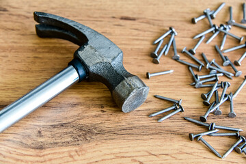 Metal hammer with nails on a wooden table. Close up. Carpenter concept