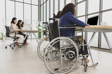 Wall Mural - Asian business women including handicap woman sitting on wheelchair working hard on laptop on the table in office. Concept for business meeting