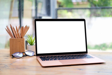 Wall Mural - Mock up computer laptop with empty screen glasses and pencil holder on wooden table.