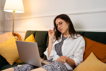 Image of young cheery positive beautiful business woman sitting indoors in office or home office using laptop computer.