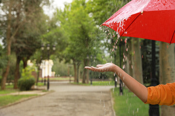 Wall Mural - Young woman with umbrella under rain in park, closeup. Space for text