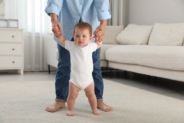 Wall Mural - Mother teaching her little baby to walk at home