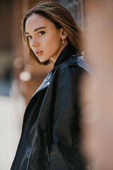 Wall Mural - Young woman in sunglasses, hat and black leather jacket posing outdoor.