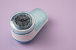 Small fabric shaver on purple background. Handed lint remover. Clothes shaver device