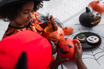 Poster - african american girl drawing on pumpkin of blurred brother