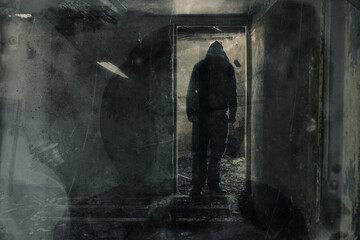 Wall Mural - A double exposure of a scary hooded figure standing in the doorway of a ruined building. With a grunge, texture vintage edit.