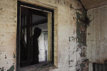 Wall Mural - A blurred, ghostly figure. Framed in a window in a decaying old abandoned house