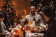 © Syda Productions - holidays, party and celebration concept - multiethnic group of happy friends having christmas dinner at home and drinking wine