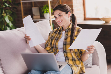 Wall Mural - Portrait of peaceful pretty people sit on sofa analyzing hold papers have good mood working from home indoors