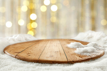 Wall Mural - Wooden table with fresh snow and a vacant seat, against a blurry golden background 