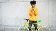 © Alessandro Biascioli - Happy African man using mobile smartphone outdoor while riding with bike in the city - Youth millennial generation lifestyle and technology concept