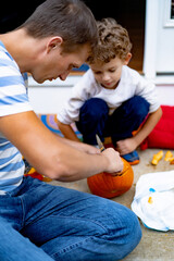 Lovely father dad helping kids to remove all the pulp from pumpkin while carving jack o lantern with family, parents with kids preparing for Halloween. Happy halloween