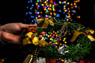 Wall Mural - Closeup of the hand holding Christmas wreath against bokeh lights background.