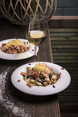 Wall Mural - Meat salad with olives and crispbread served on white plates and with a glass of champagne