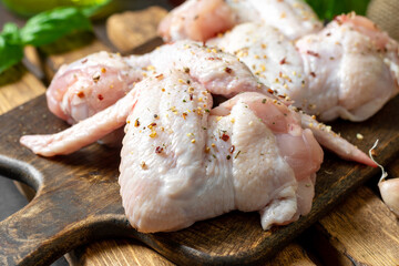 Wall Mural - Raw chicken wings on a wooden board on a dark culinary background closeup	