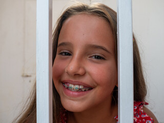 cute teenage caucasian smiling girl with braces looking at the camera behind the bars