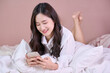 woman smile and use phone on bed