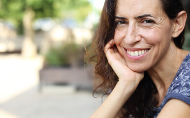 Portrait of beautiful natural 50 years old woman sitting in street cafe