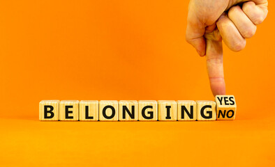 Belonging yes or no symbol. Businessman turns a wooden cube and change words 'belonging no' to 'belonging yes'. Beautiful orange background. Business and belonging yes or no concept, copy space.