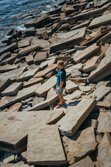 Wall Mural - A young man on a rocky beach made of natural stones in the Crimea