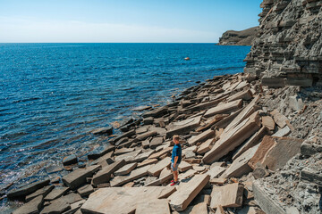 Wall Mural - A young man on a rocky beach made of natural stones in the Crimea