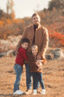 © Evgeniya Grande - Portrait of a caucasian father hugging his children in beautiful outfits on a sunny autumn day in nature park. Family happiness concept.