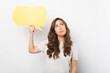 © Vulp - Beautiful confused woman is holding a speech bubble while looking up thoughtful over white background.