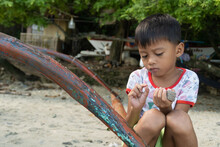 Traditional Village Boy Playing On Grandfather's  Banka Boat. At Home On The Beach.  Bignayan Village, The Philippines