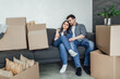 © Тарас Нагирняк - Couple resting on couch after moving in, man and woman relaxing on sofa just moved into apartment with cardboard boxes on floor!