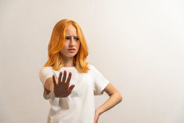 Wall Mural - Portrait of a teenage girl with red hair and a white T-shirt say no on a light background