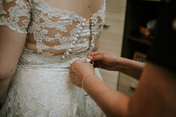 Sticker - Closeup shot of female hands tying a bow on the back of the bride dress